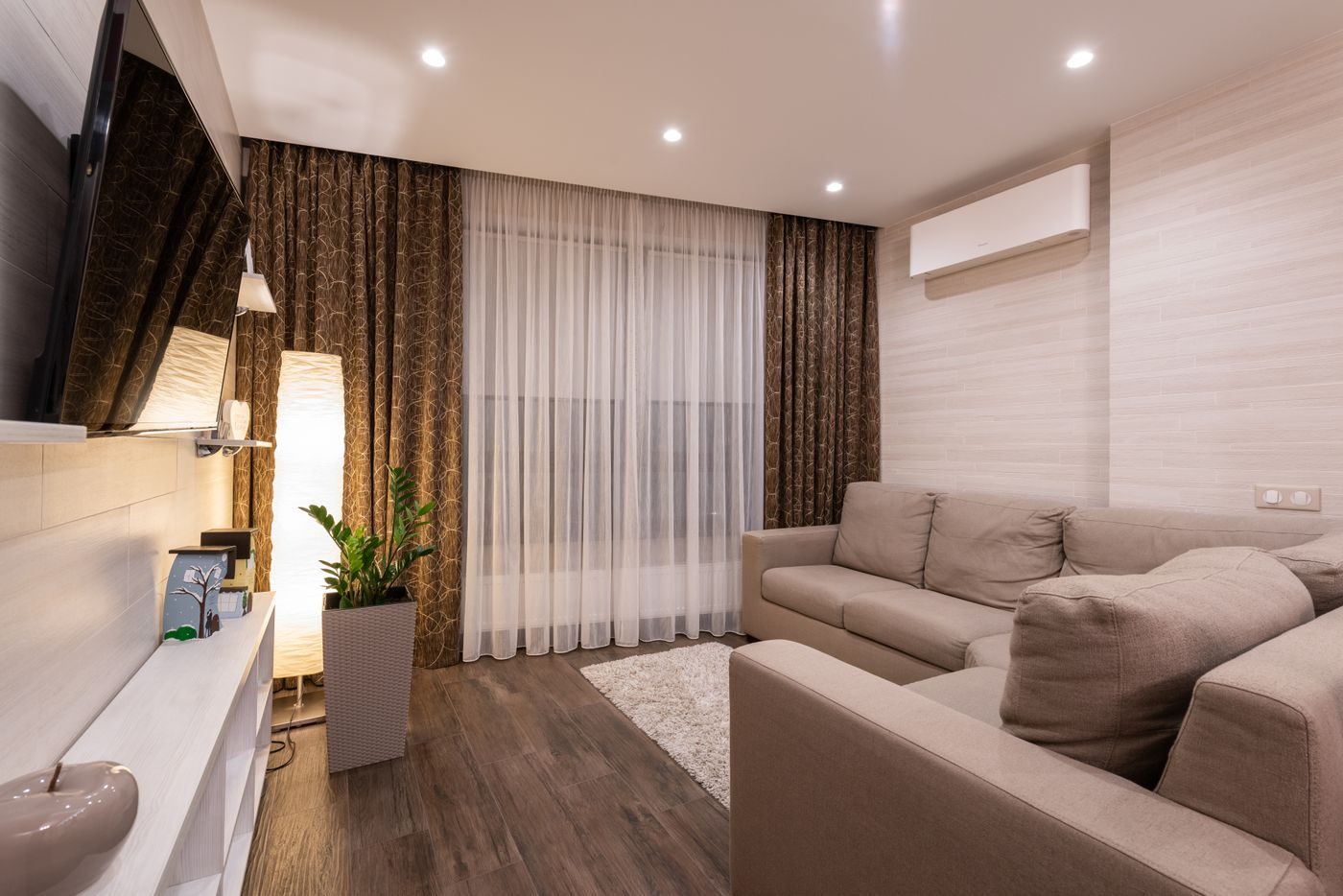 Warmly lit living room in the evening with a wall mounted air to air heat pump unit above the window